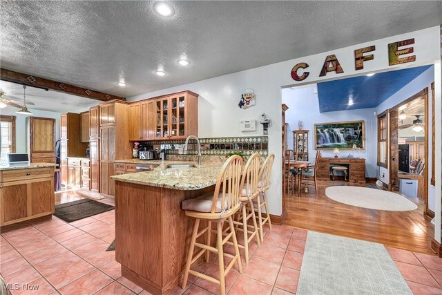 kitchen with sink, light tile patterned flooring, kitchen peninsula, and a kitchen bar