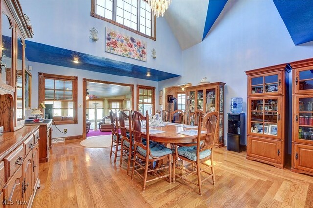 dining space featuring light hardwood / wood-style floors, a high ceiling, and a notable chandelier