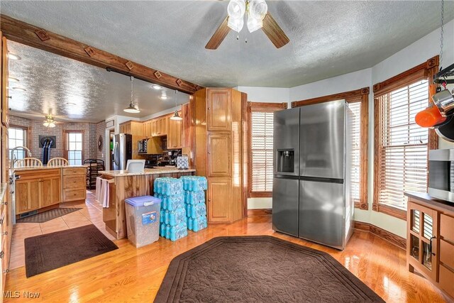 kitchen with pendant lighting, stainless steel fridge, light hardwood / wood-style flooring, stainless steel refrigerator, and a textured ceiling