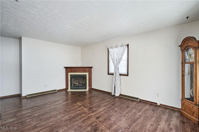 unfurnished living room featuring a textured ceiling and dark hardwood / wood-style flooring