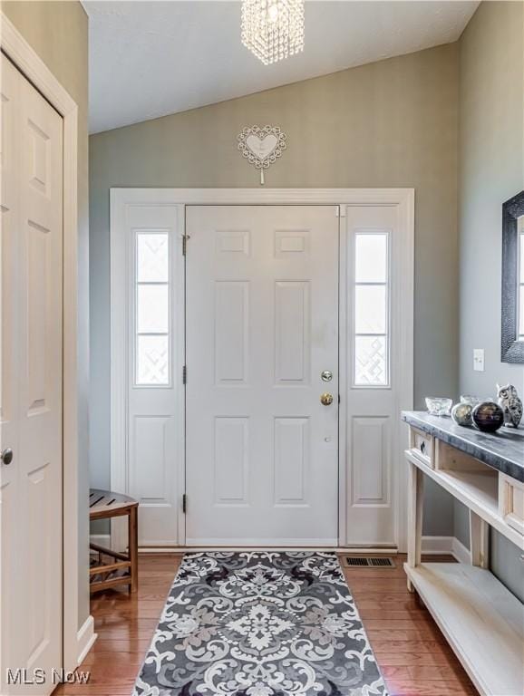 entrance foyer with hardwood / wood-style flooring, lofted ceiling, and an inviting chandelier