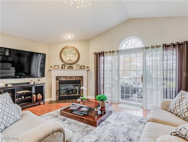 living room with hardwood / wood-style flooring, a high end fireplace, and vaulted ceiling