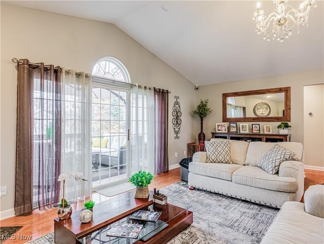 living room featuring an inviting chandelier, wood-type flooring, and vaulted ceiling