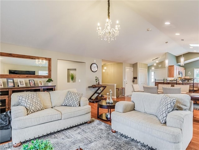 living room featuring lofted ceiling, a chandelier, and light hardwood / wood-style flooring