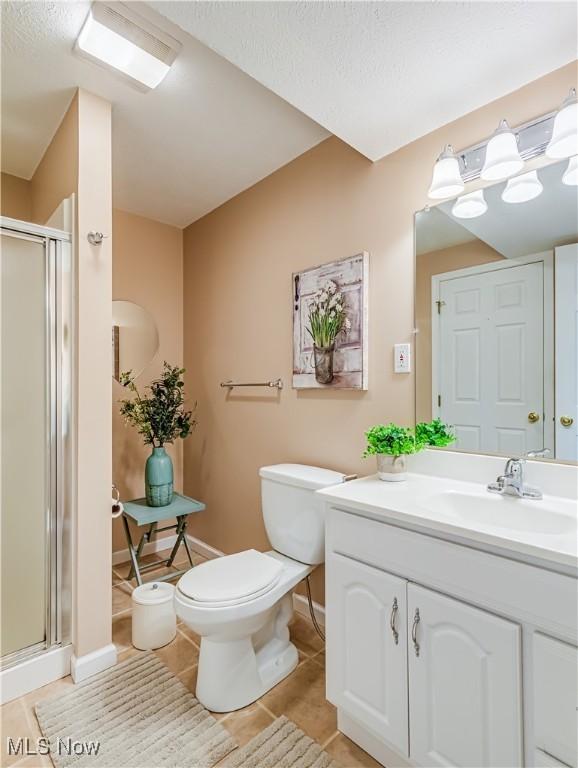 bathroom featuring toilet, vanity, a shower with door, and tile patterned flooring