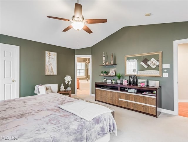 bedroom featuring ceiling fan, ensuite bath, vaulted ceiling, and light carpet