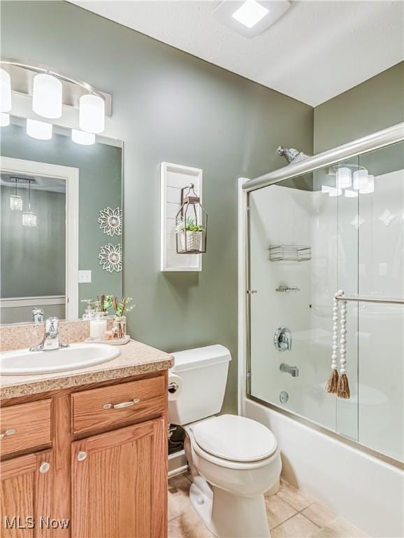 full bathroom with vanity, bath / shower combo with glass door, tile patterned floors, and toilet