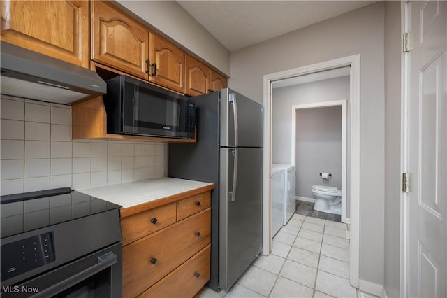 kitchen with electric stove, washer and clothes dryer, stainless steel fridge, backsplash, and ventilation hood