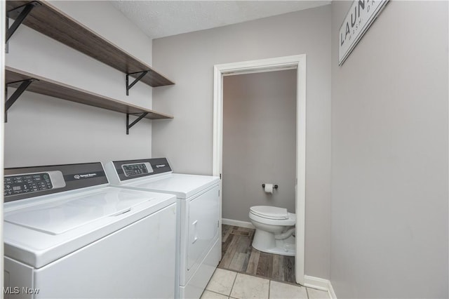 laundry room featuring light tile patterned flooring, washing machine and dryer, and a textured ceiling