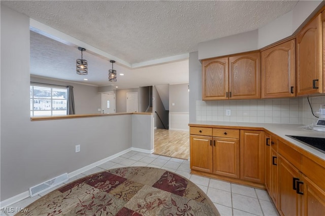 kitchen featuring pendant lighting, light tile patterned floors, backsplash, and a textured ceiling