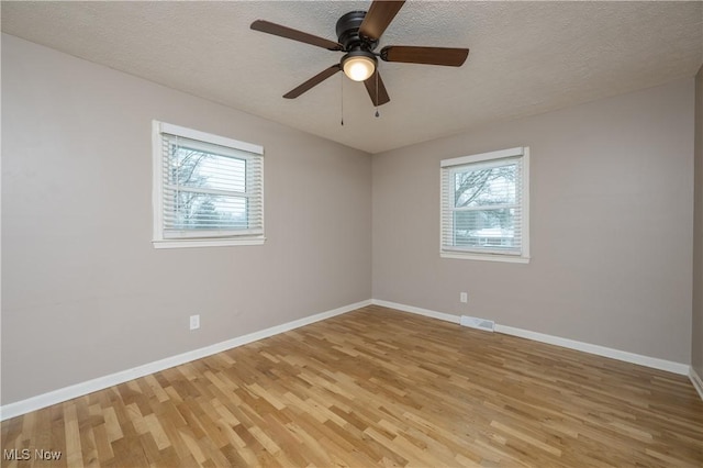 empty room with plenty of natural light, hardwood / wood-style floors, a textured ceiling, and ceiling fan