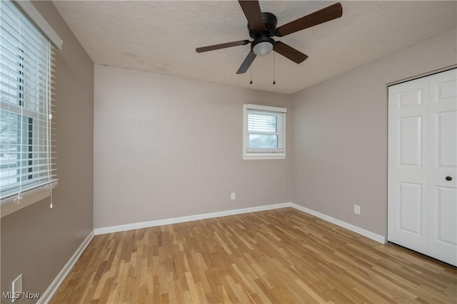 unfurnished bedroom featuring a textured ceiling, a closet, ceiling fan, and light wood-type flooring