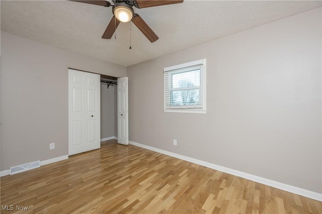 unfurnished bedroom with a textured ceiling, light hardwood / wood-style flooring, a closet, and ceiling fan