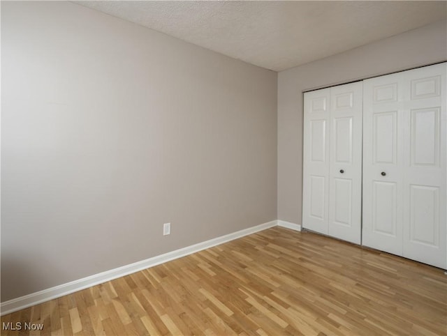 unfurnished bedroom featuring hardwood / wood-style flooring, a textured ceiling, and a closet