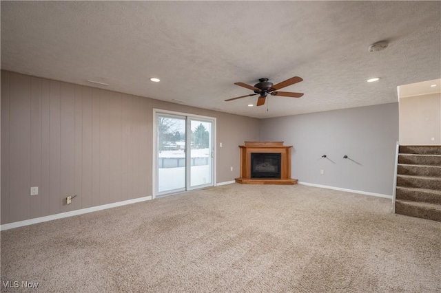 unfurnished living room with ceiling fan, carpet, and a textured ceiling