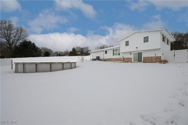 snow covered house featuring a fenced in pool