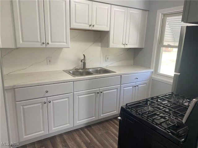 kitchen with white cabinetry, sink, stainless steel fridge, dark hardwood / wood-style flooring, and black range with gas cooktop