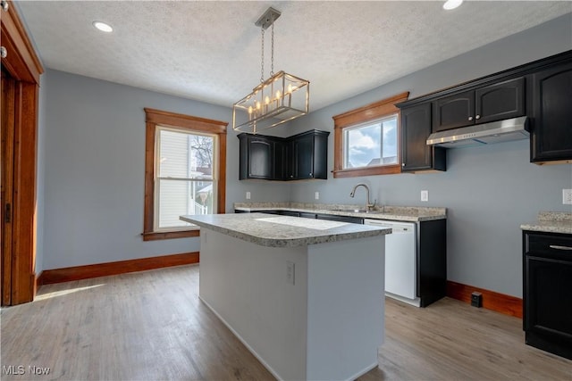 kitchen featuring white dishwasher, sink, a wealth of natural light, and a center island