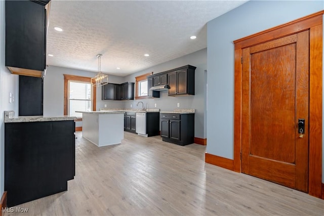 kitchen featuring a kitchen island, sink, pendant lighting, and light wood-type flooring