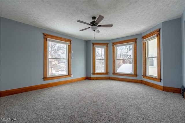 unfurnished room featuring ceiling fan, carpet floors, a wealth of natural light, and a textured ceiling