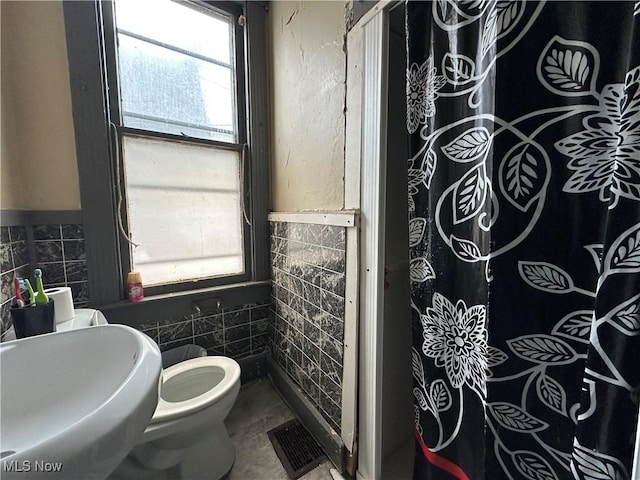 bathroom featuring tile walls, sink, and toilet