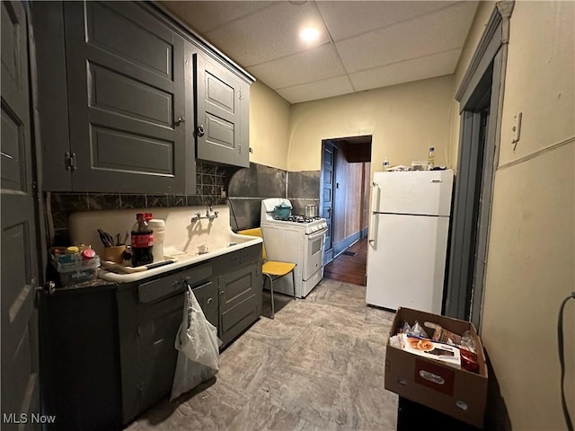 kitchen with tasteful backsplash, white appliances, and a drop ceiling