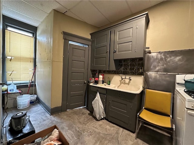 bathroom with backsplash and a paneled ceiling