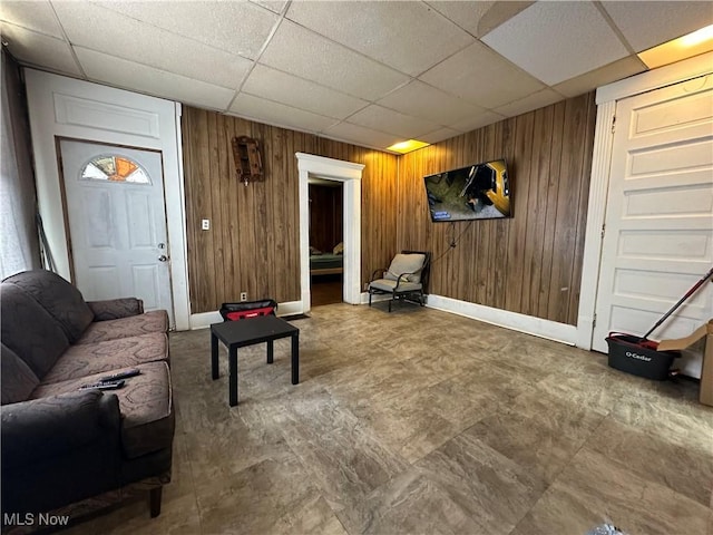 living room featuring wooden walls and a drop ceiling