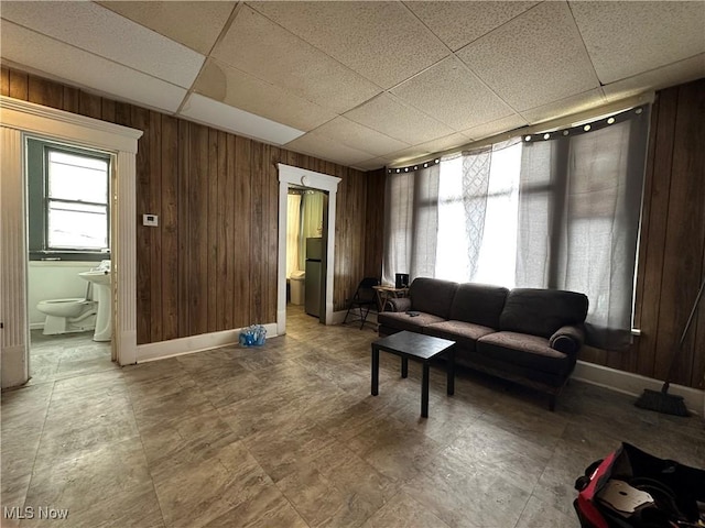 living room featuring a drop ceiling and wood walls