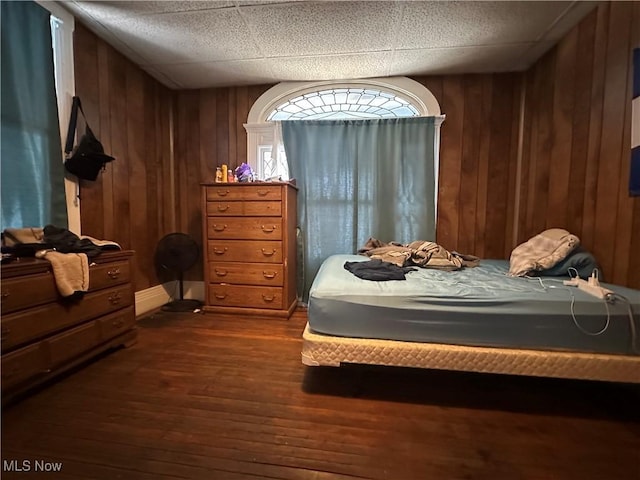 bedroom featuring dark hardwood / wood-style flooring and wooden walls