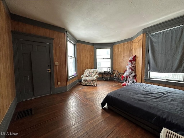 bedroom featuring wooden walls and dark hardwood / wood-style floors