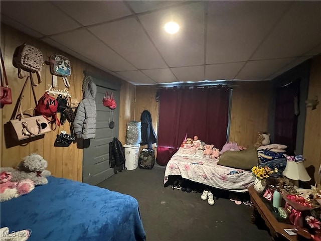 bedroom with a paneled ceiling and wooden walls