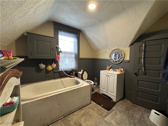 bathroom featuring vaulted ceiling, a textured ceiling, and a tub