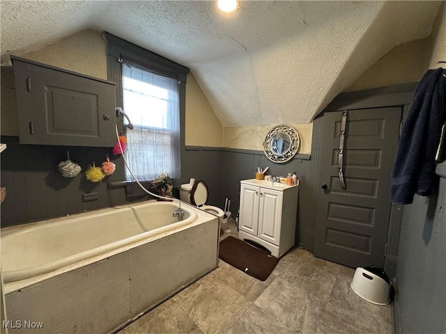 bathroom with vanity, lofted ceiling, a washtub, and a textured ceiling