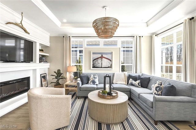 living room with crown molding, plenty of natural light, a tray ceiling, and hardwood / wood-style floors