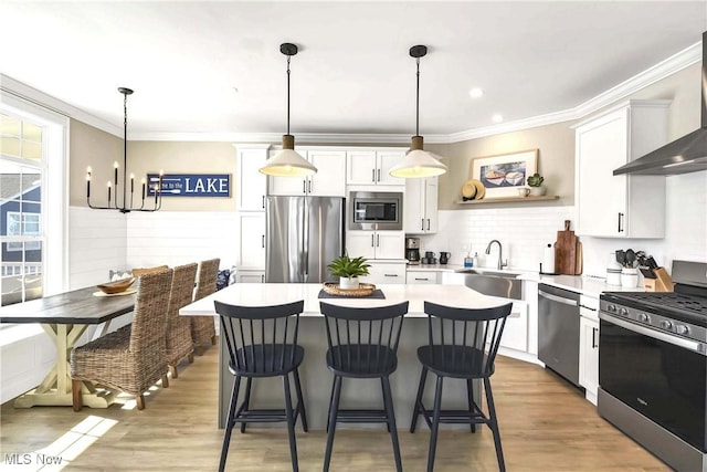 kitchen with sink, wall chimney range hood, white cabinets, and appliances with stainless steel finishes