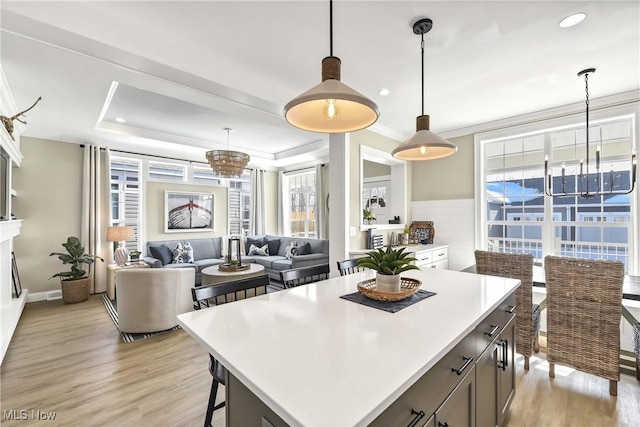 kitchen with hanging light fixtures, crown molding, a center island, and light hardwood / wood-style floors