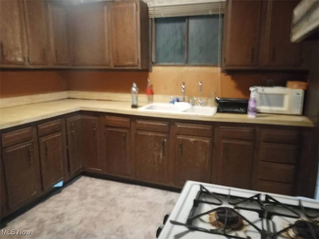 kitchen featuring white appliances, sink, and dark brown cabinets