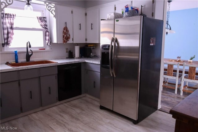 kitchen featuring stainless steel refrigerator with ice dispenser, decorative light fixtures, dishwasher, and sink