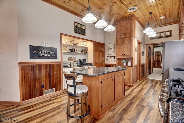 kitchen featuring a breakfast bar area, wood ceiling, a center island, light wood-type flooring, and stainless steel appliances