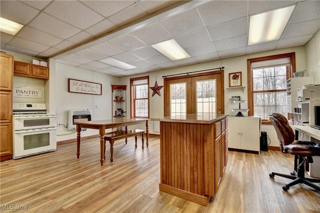 kitchen with double oven range, heating unit, a drop ceiling, and light hardwood / wood-style flooring