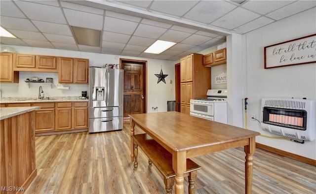 kitchen featuring white gas stove, heating unit, a paneled ceiling, light wood-type flooring, and stainless steel fridge