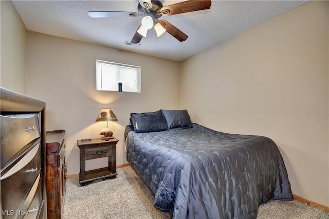 bedroom with a textured ceiling, light colored carpet, and ceiling fan