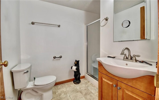 bathroom featuring vanity, a shower with shower door, and toilet