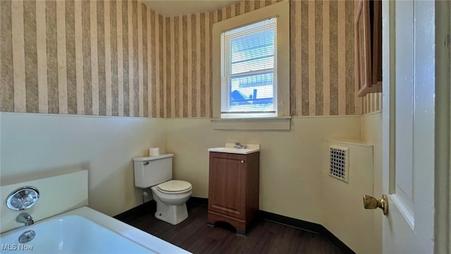 bathroom featuring vanity, a bath, hardwood / wood-style floors, and toilet