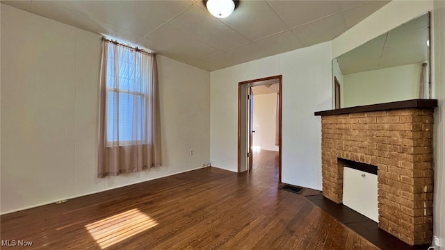 unfurnished living room with a brick fireplace and dark hardwood / wood-style floors