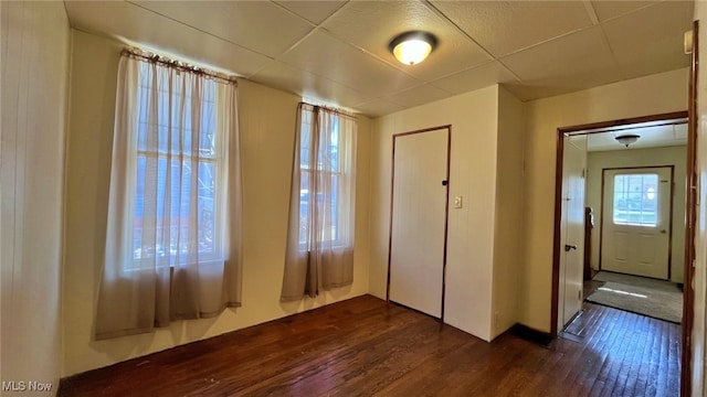 unfurnished bedroom featuring a closet, dark hardwood / wood-style floors, and multiple windows