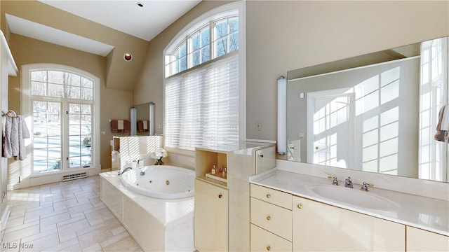 bathroom featuring vaulted ceiling, tiled bath, and vanity