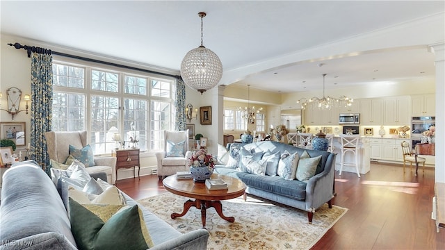 living room with crown molding, a chandelier, and light hardwood / wood-style flooring