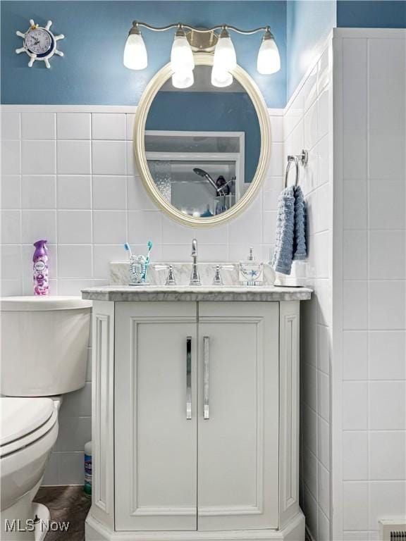 bathroom featuring vanity, toilet, and tile walls